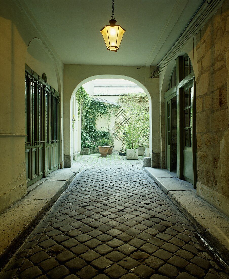 Durchgang mit Kopfsteinpflastern zu dem Garten eines französischen Stadthauses