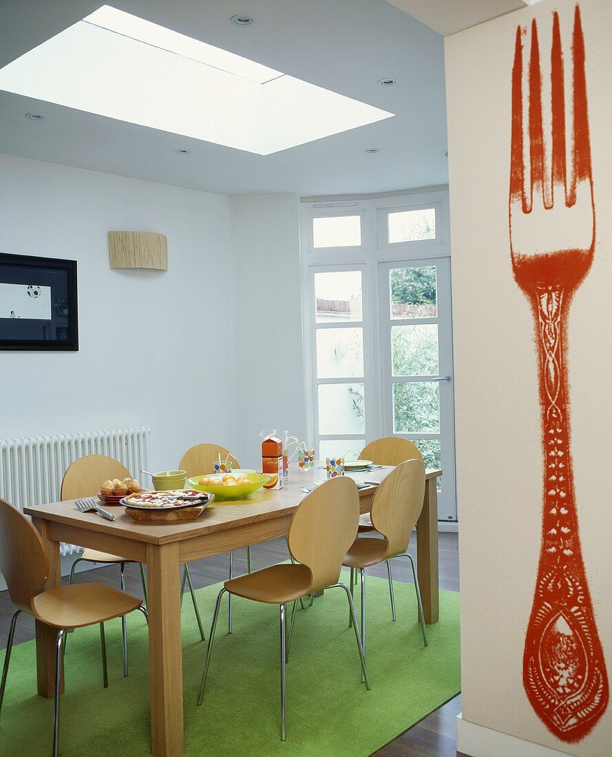 Tisch aus Holz und Stühle im Bauhausstil im minimalistischem Esszimmer und Gabelmotiv als Wandbild