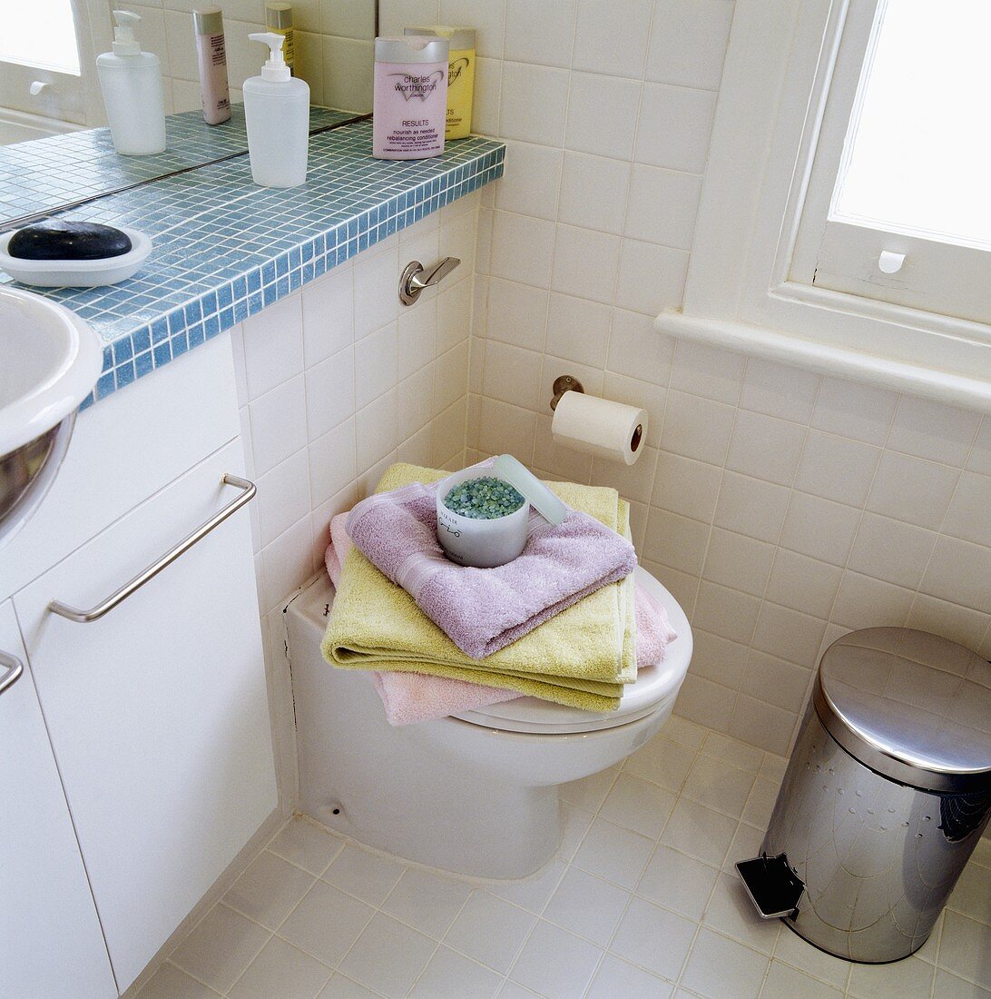 Toilette neben Waschtisch mit blauen Mosaikfliesen auf Ablage in kleinem Bad