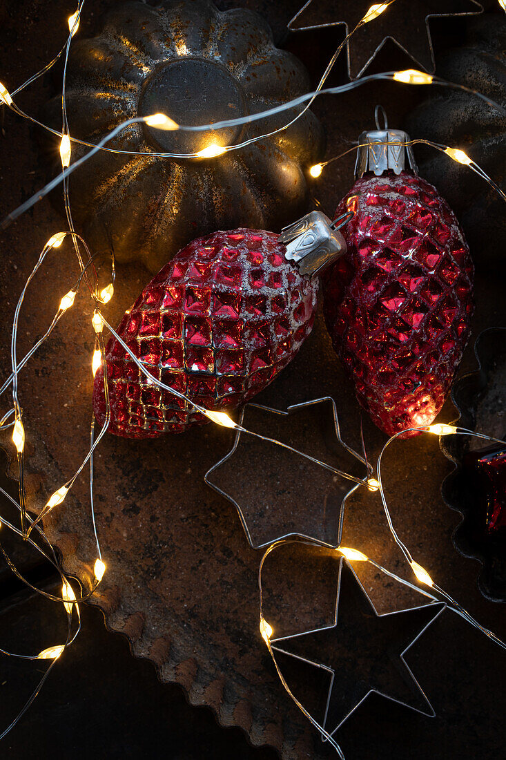  Old cookie cutters on tin with old Christmas tree decorations and fairy lights 