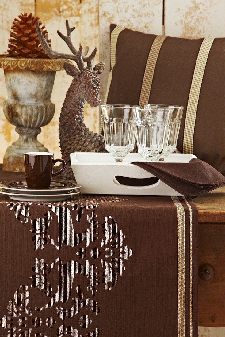 Weichnachtlicher Tisch mit brauner Tischdecke, Weingläsern und Tasse