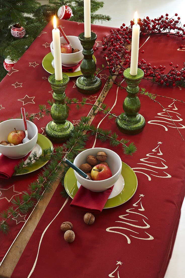 Weihnachtlich gedeckter Tisch mit roter Tischdecke und Kerzen