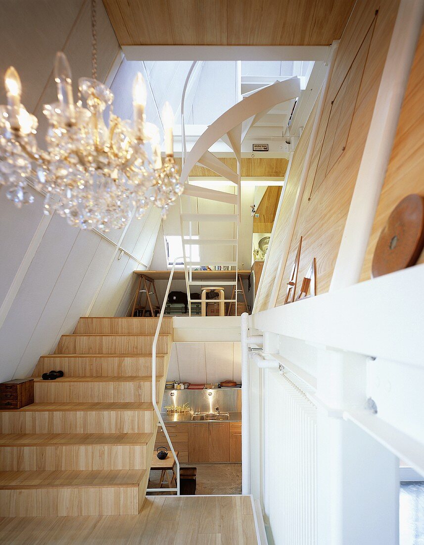 An open staircase with wooden stairs and a view into a kitchen onto a study corner
