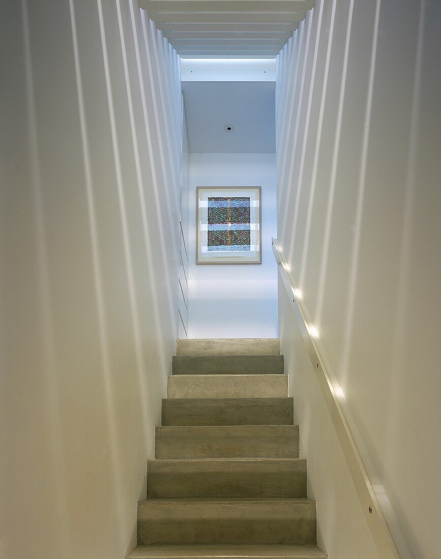 A narrow modern stairway with a play of light and shade on the wall