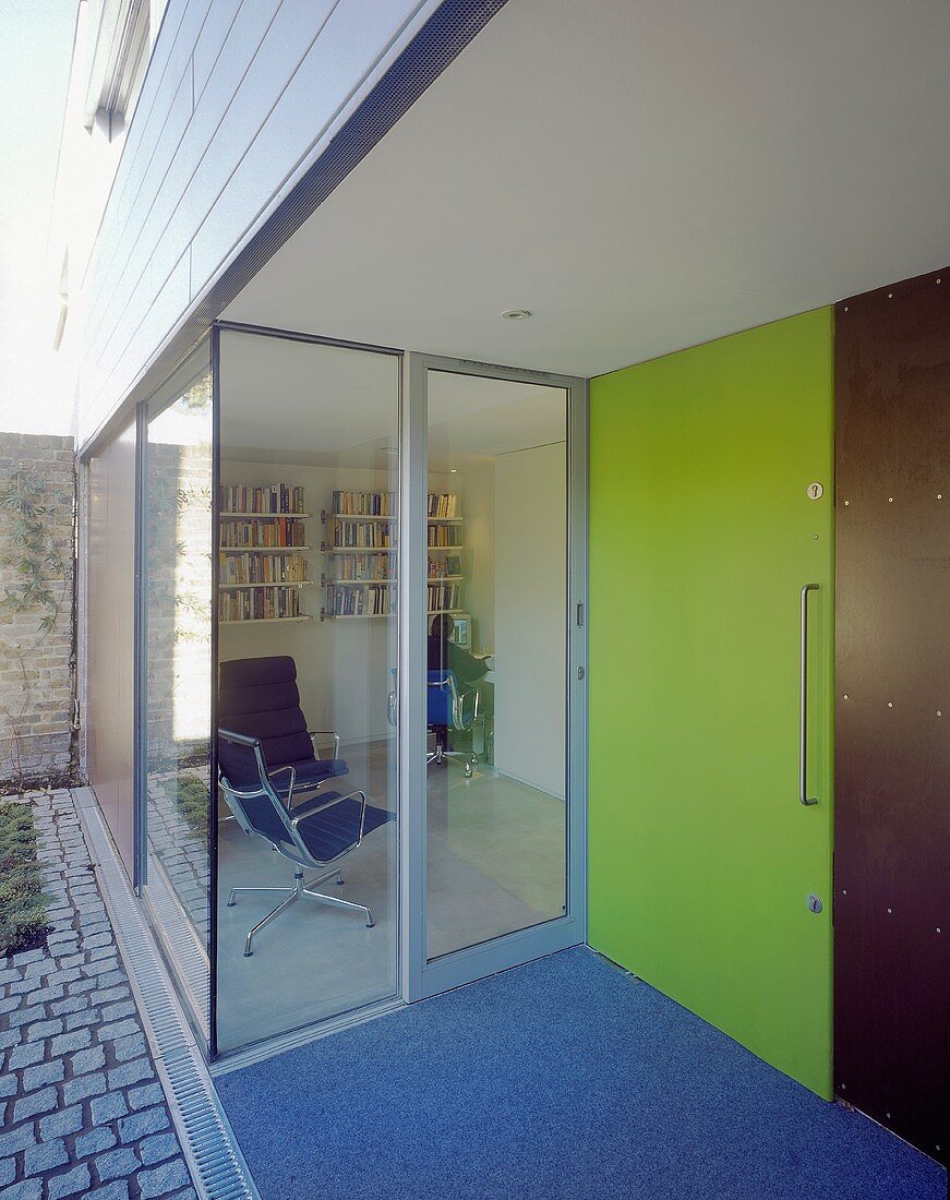 A green front door next to a glass facade of a newly built house
