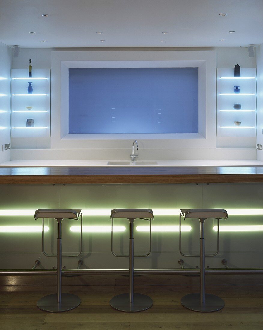 An open designer kitchen with an illuminated bar