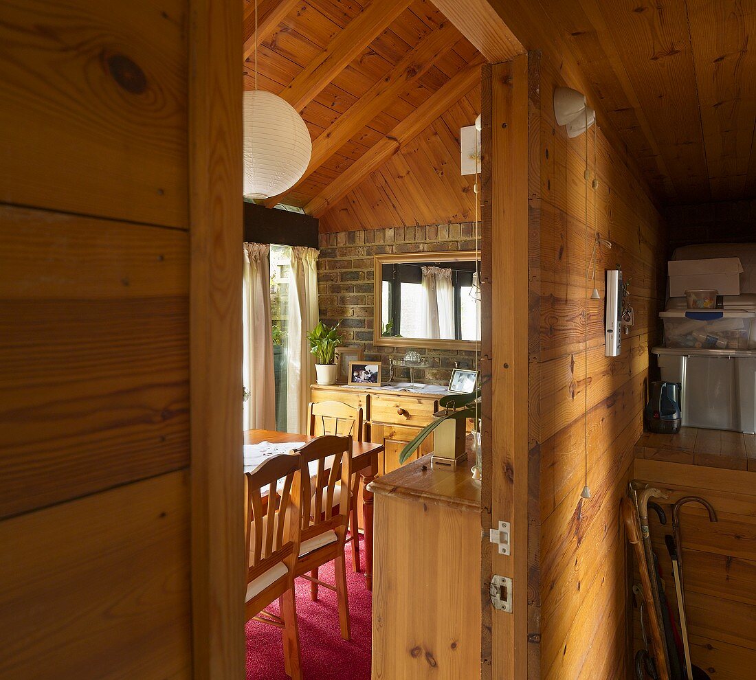 An anteroom in a wooden house with a view through an open door into a dining room