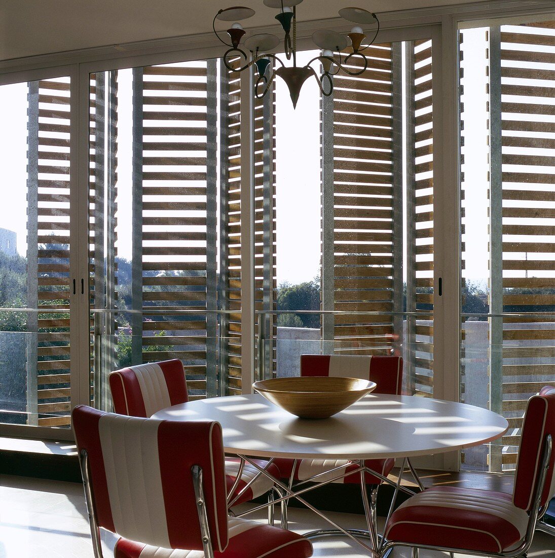 A round table and chairs in front of terrace windows with wooden shutters