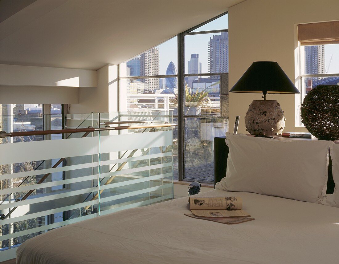 An open-plan bedroom on a mezzanine floor with a view of the city