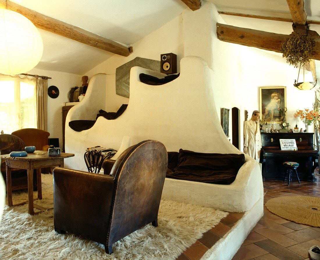 Sitzgruppe auf Flokati mit alten Holz-Leder-Sesseln und organisch geformten Steinsitzen in französischem Landhaus