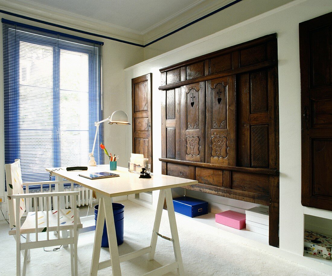 Blaue Jalousie, Regiestuhl und Schreibtischplatte im Kontrast zu Einbauschränken mit antiken, geschnitzten Holztüren