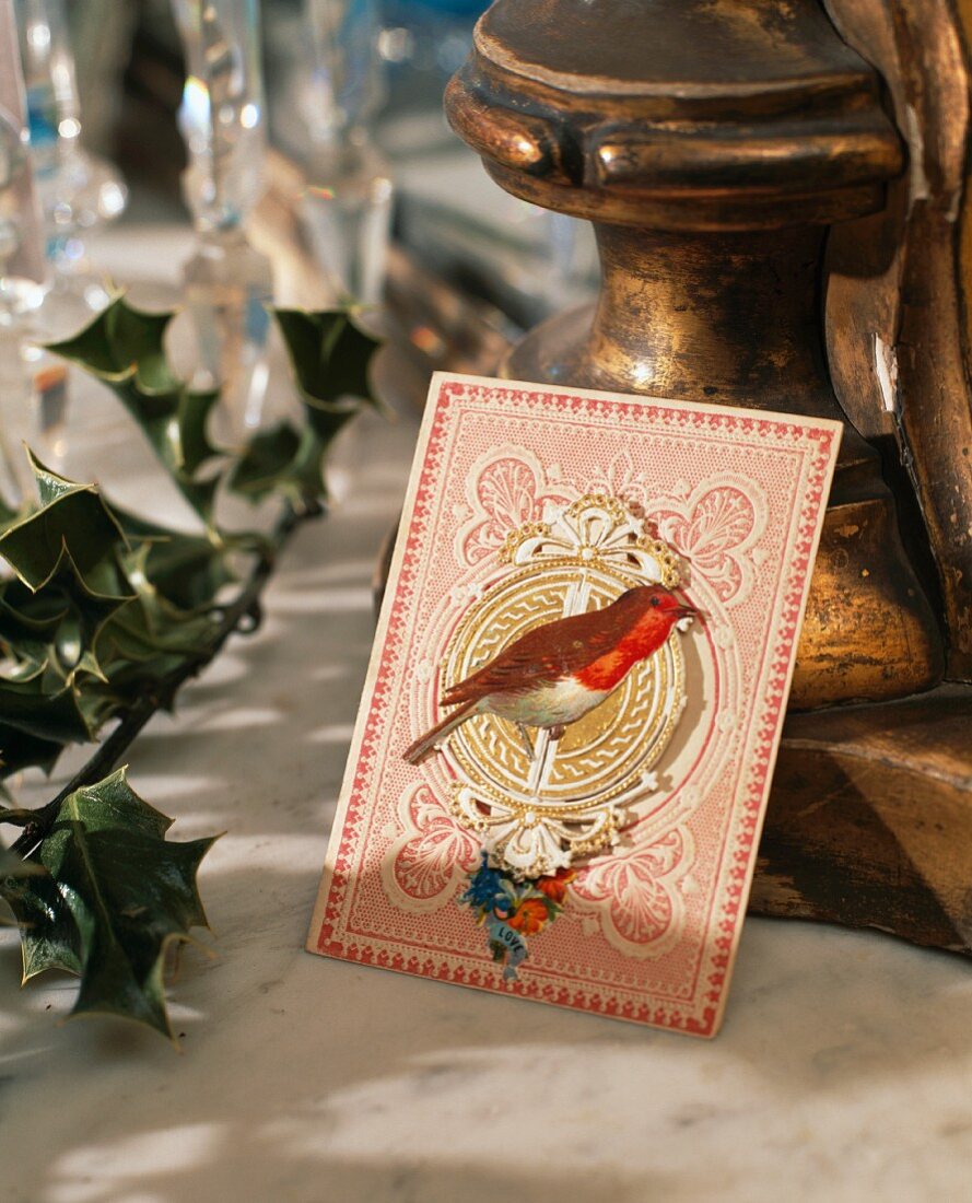 Gemaltes Rotkehlchen auf altmodischer Weihnachtskarte als Teil einer Tischdekoration