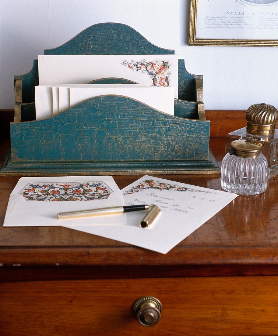 Antikes Schreibtisch-Ambiente mit Briefständer aus Holz und geöffnetem Füller auf Briefpapier mit Paisley-Muster