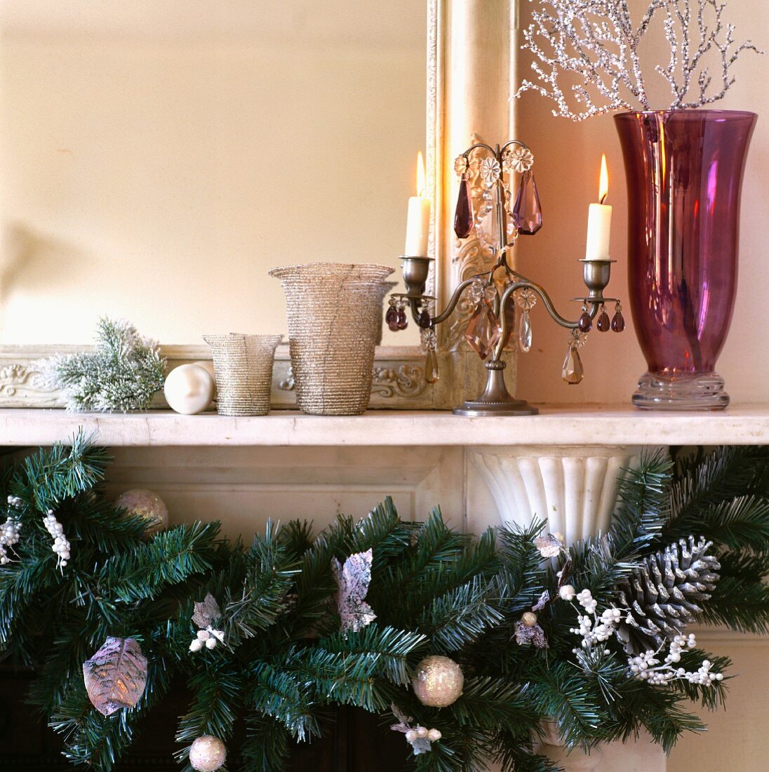 Leuchter aus Zinn, violette Glasvase und Weihnachtsdeko in Silber auf weißem Kaminsims