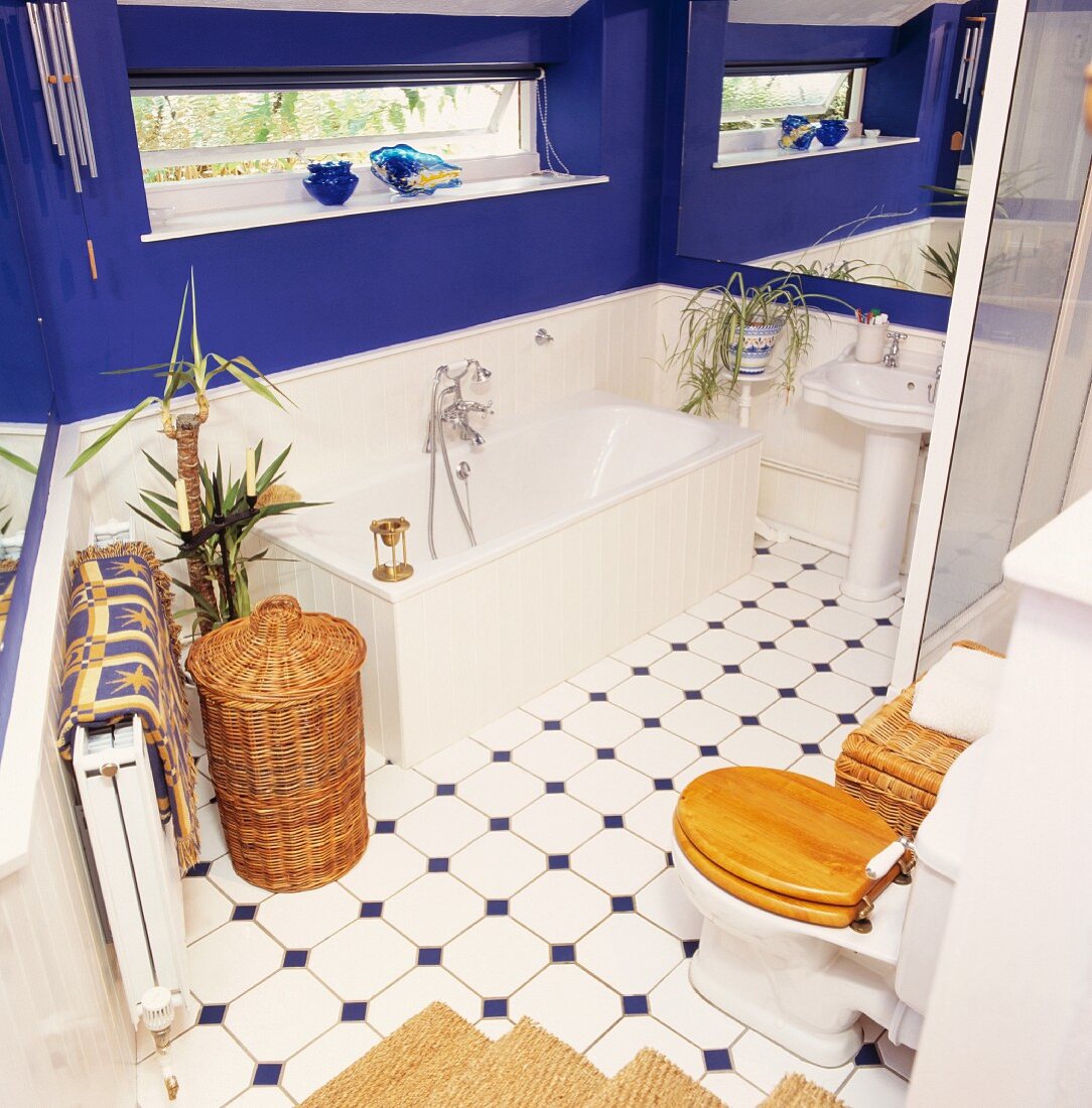 Knallblau gestrichene Wände in weißem Landhaus-Badezimmer mit Weidenkörben und Toilettensitz aus Holz