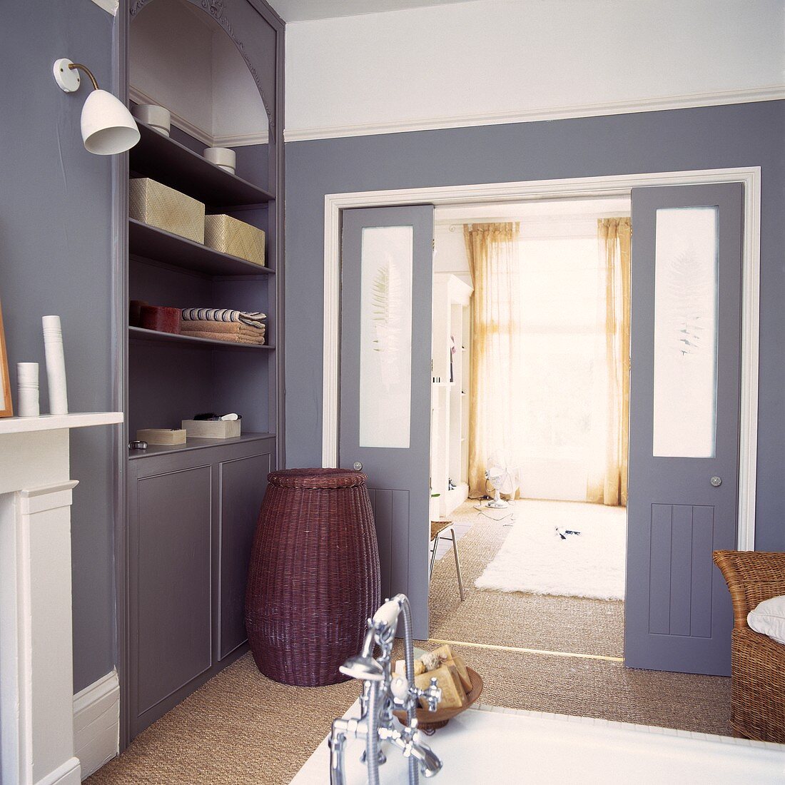 Ein Badezimmer mit grauen Einheiten und Schiebetüren zum Schlafzimmer