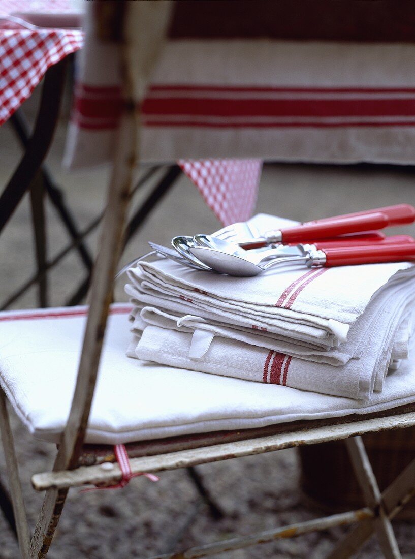 Rot-weiße Geschirrtücher mit Besteck auf einem alten Gartenstuhl