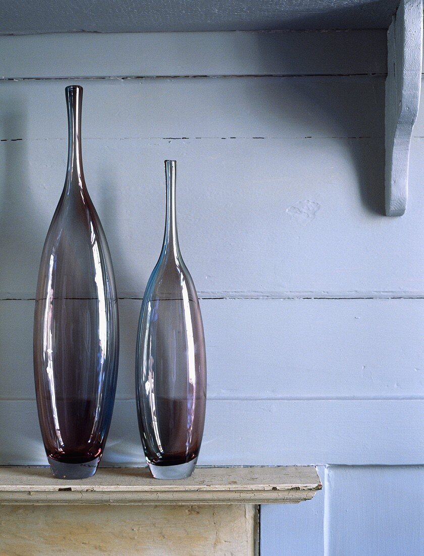 Zwei Glasvasen vor Holzvertäfelung