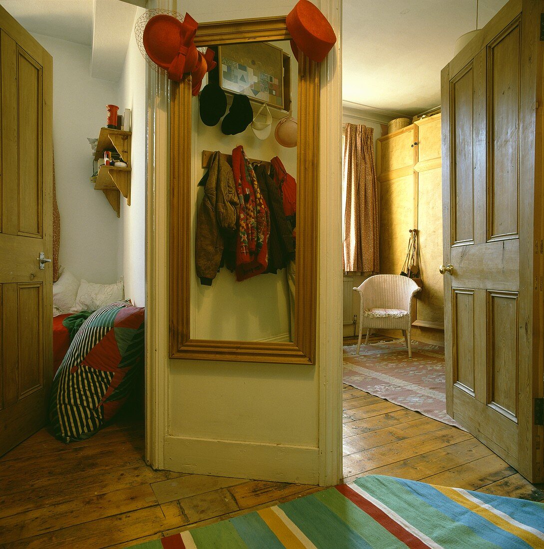 Dielenwand mit Reflektion einer Garderobe in Spiegel zwischen zwei geöffneten Zimmertüren