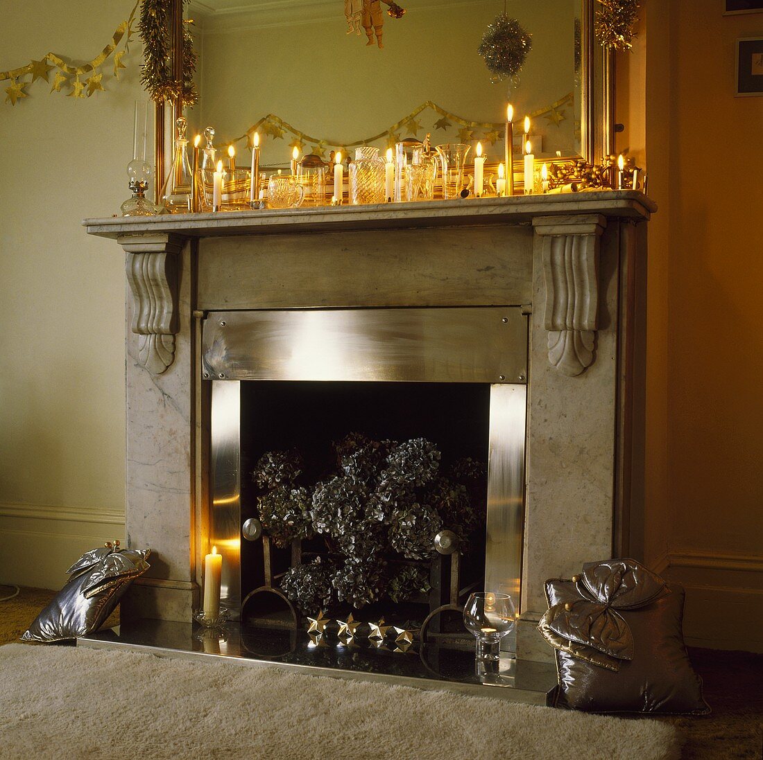 Viele brennende Kerzen und Weihnachtsdekoration auf Marmorkamin mit Edelstahlrahmen