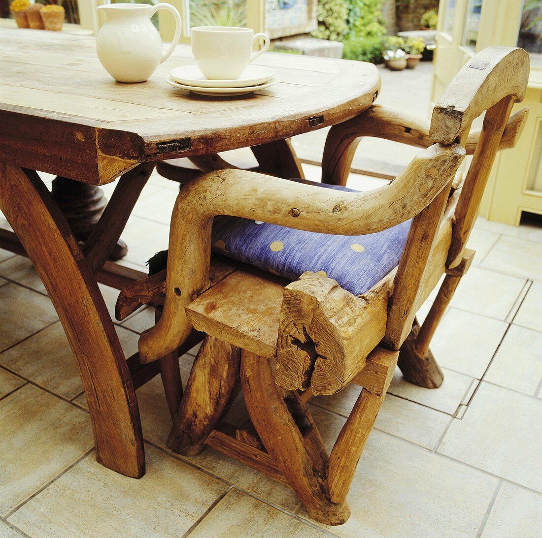 Rustikale Stuhlkonstruktion mit Verwendung gewachsener Äste an Holztisch mit weißem Teeservice