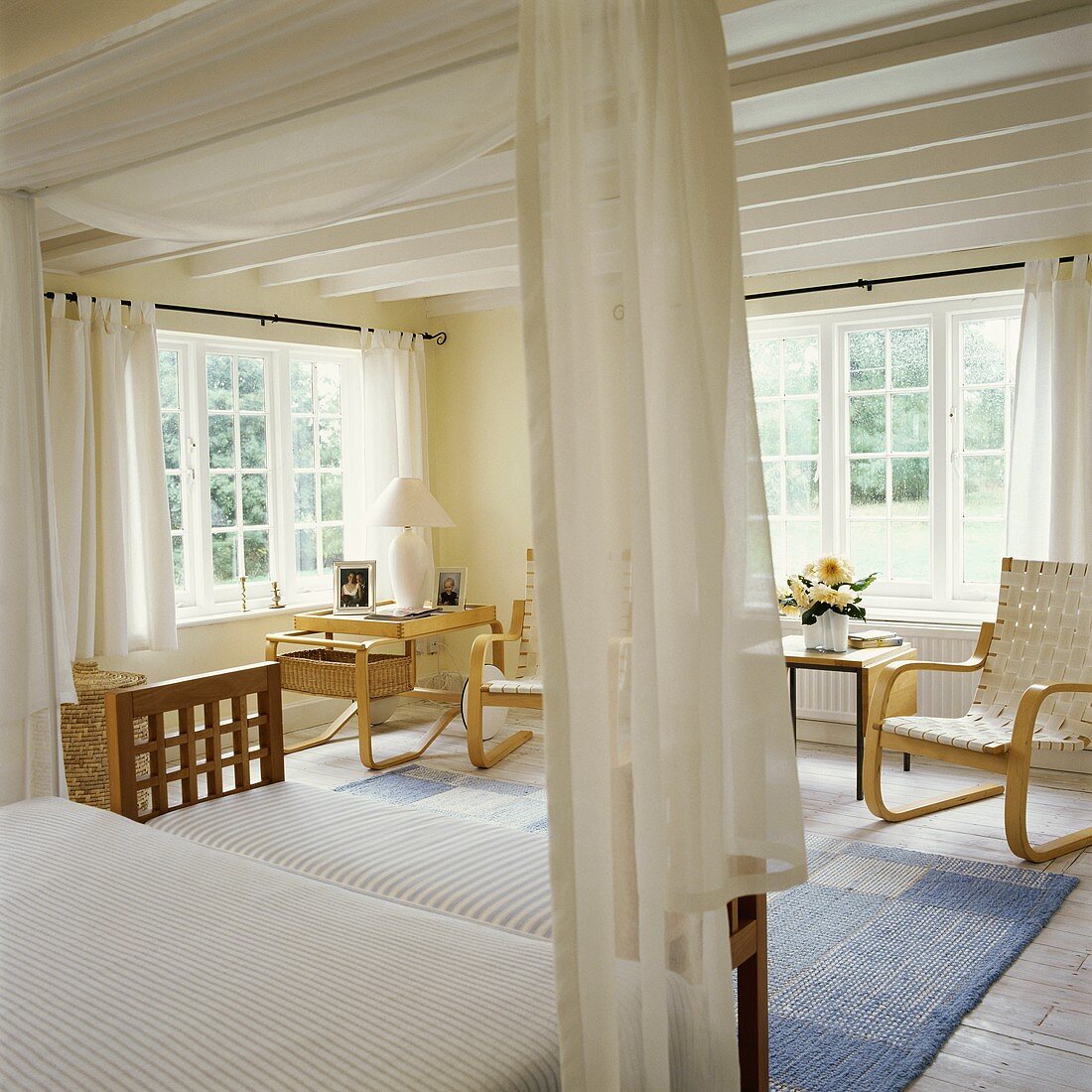 Skandinavische Sessel mit Gurtbezügen in lichtem, weissen Schlafzimmer mit pastellblauem Webteppich