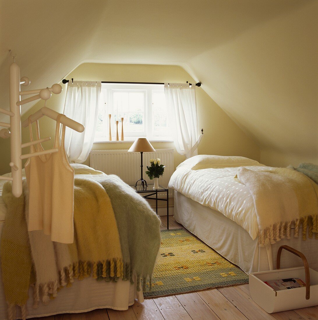 Pastellfarbene Mohairdecken auf zwei Einzelbetten in Schlafzimmer unterm Dach mit Dielenboden