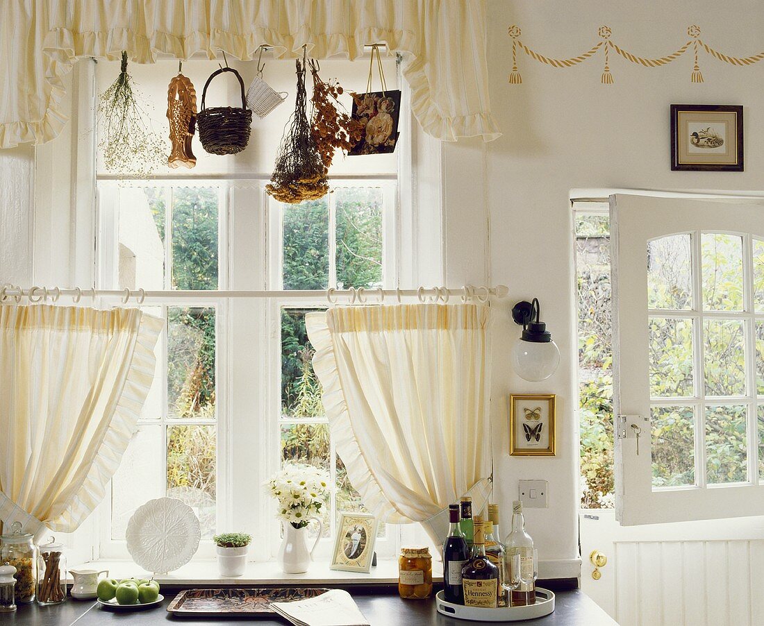 Eine Arbeitsplatte vor dem Fenster mit weissen Vorhängen in einer Küche