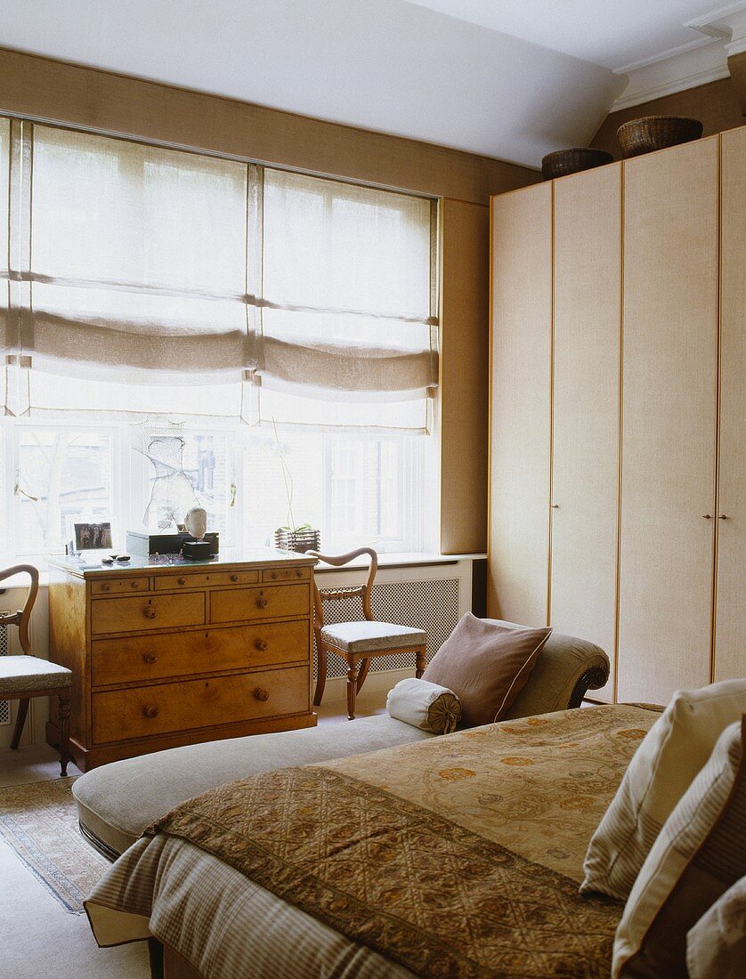 Beige Leinen Jalousien am Fenster über antike Truhe mit Schubladen im neutralen Schlafzimmer mit Einbauschrank