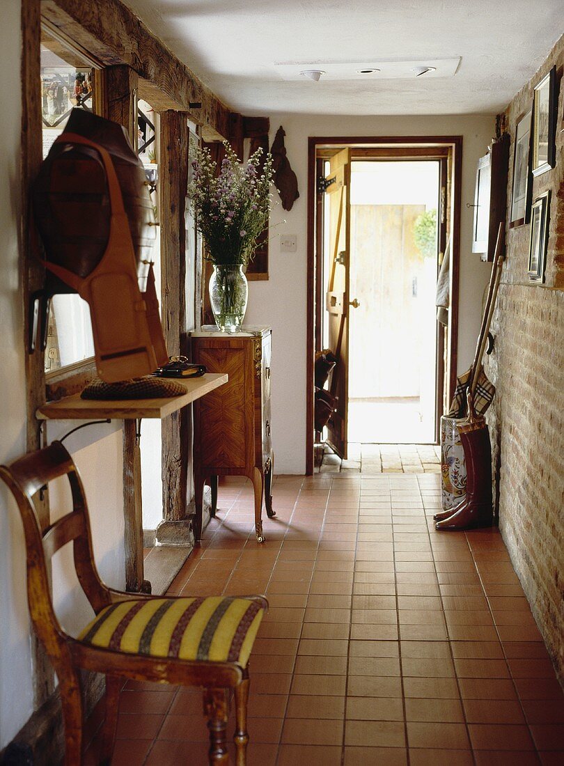 Terrakotta-Bodenfliesen auf einem Eingangsflur mit einem antiken Stuhl und offener Tür