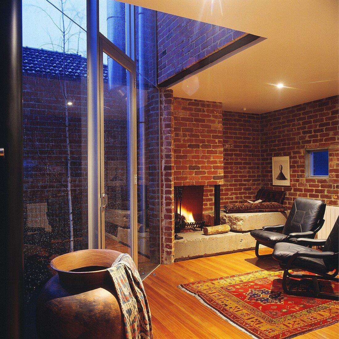 Ein modernes Wohnzimmer mit einer offenen Feuerstelle und einer großen Fensterfront