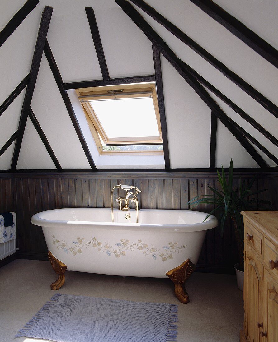 Eine freistehende Badewanne steht unter einem Velux-Dachfenster des Badezimmers eines Fachwerkhauses