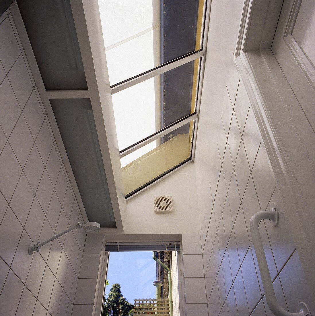 Ein verlängertes Glasdach wurde über eine Dusche des modernen weißgefliesten Badezimmers angebracht