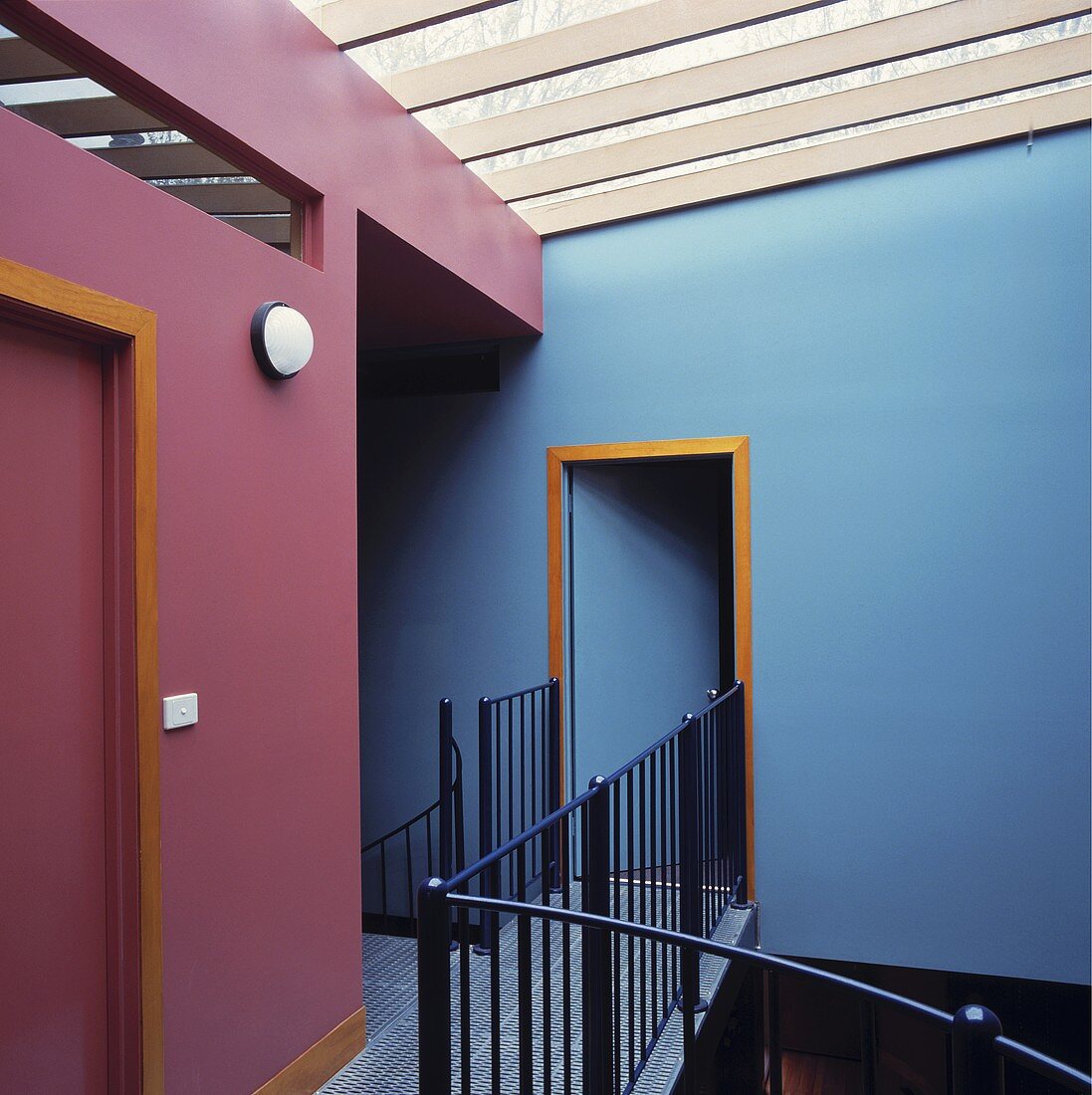 Ein moderner Stockwerkvorraum mit lila-blauen Wänden und ein schwarzes Metallgeländer