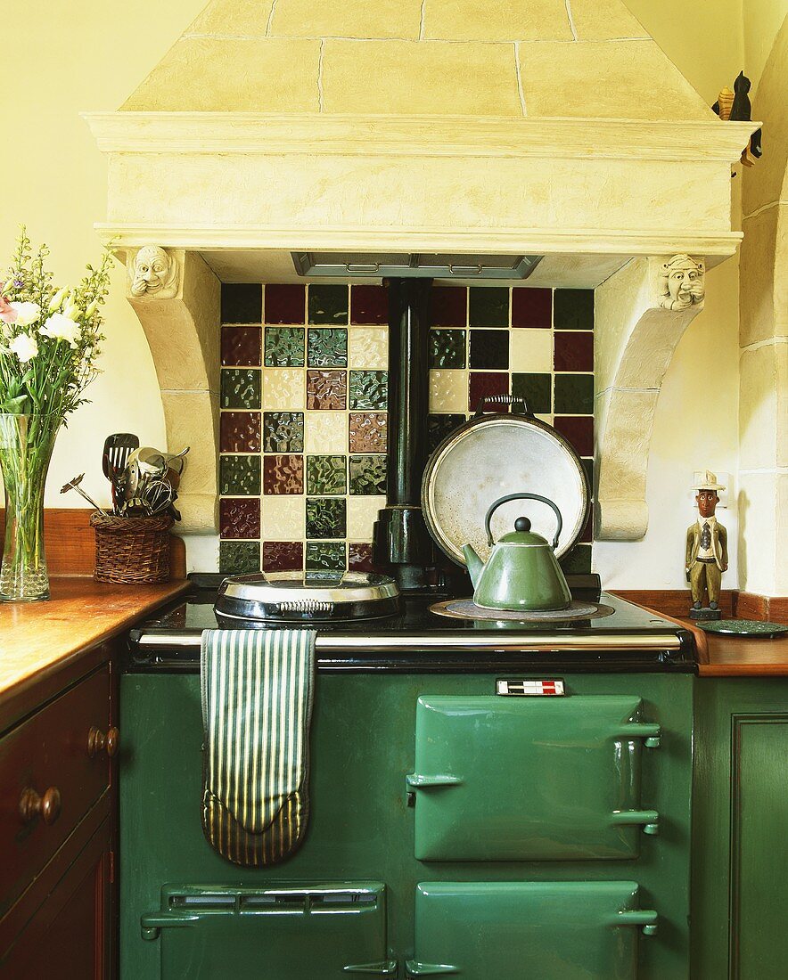 Küche in altem Haus mit grünem Aga-Ofen unter antikem Kaminabzug mit Funktion als Dunstabzugshaube