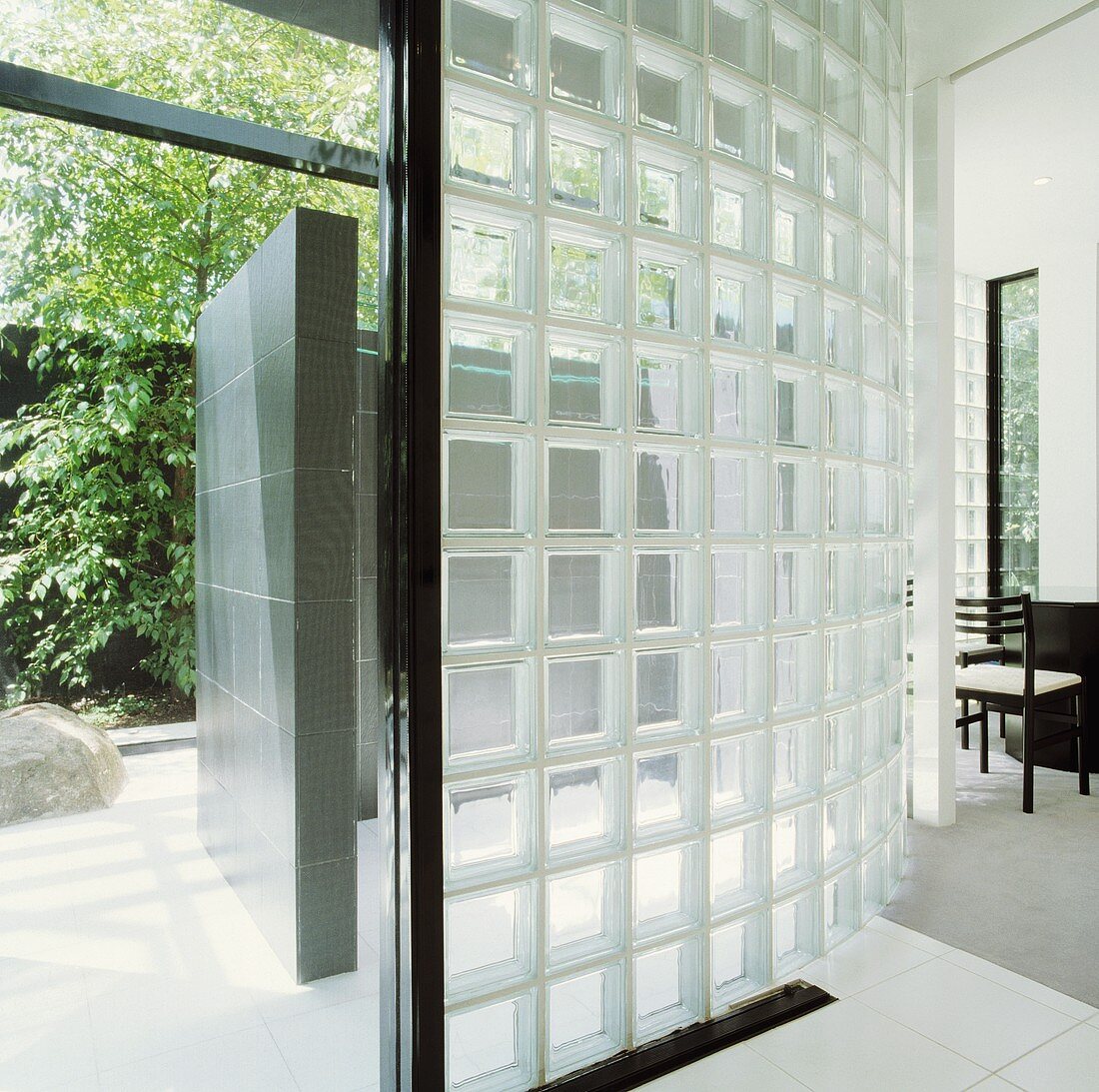 Gebogene Wand aus Glasbausteinen in modernem Haus mit offener Tür und Blick in Garten