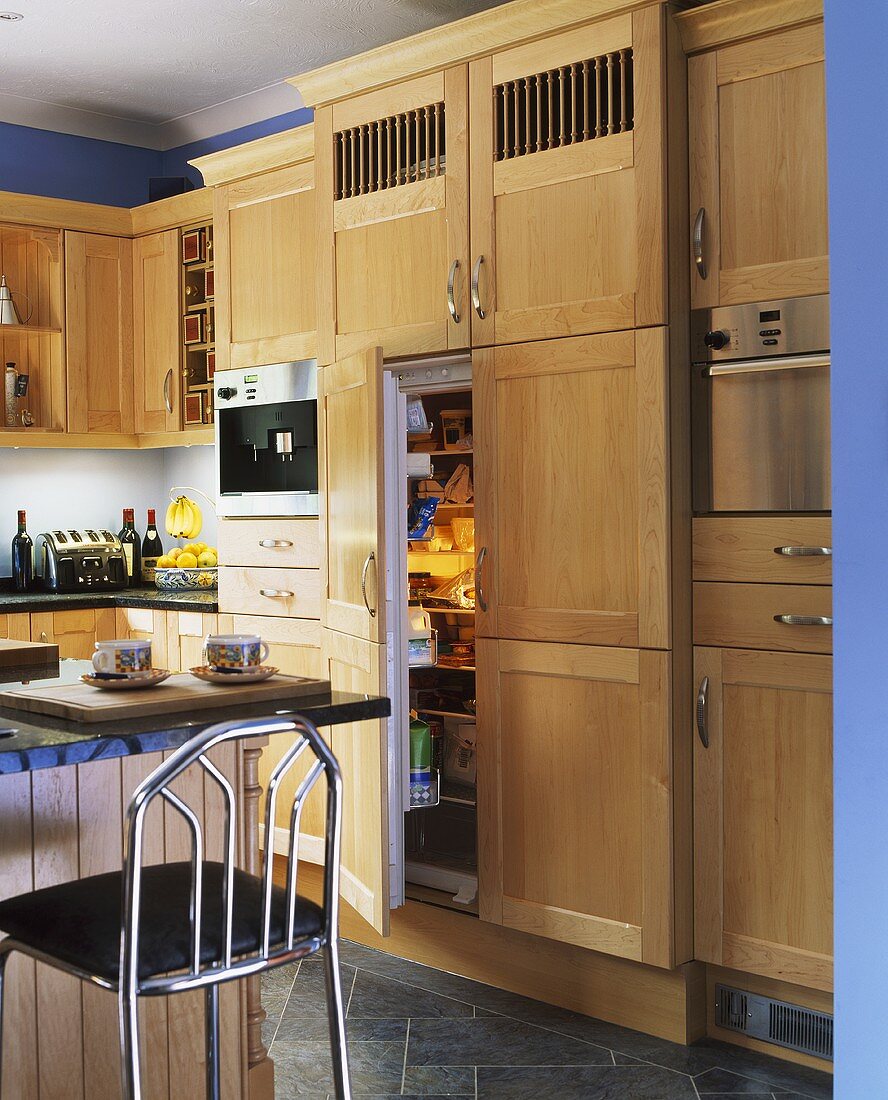 Moderne Küche mit Holzfronten, offener Kühlschranktür und Frühstücksbar