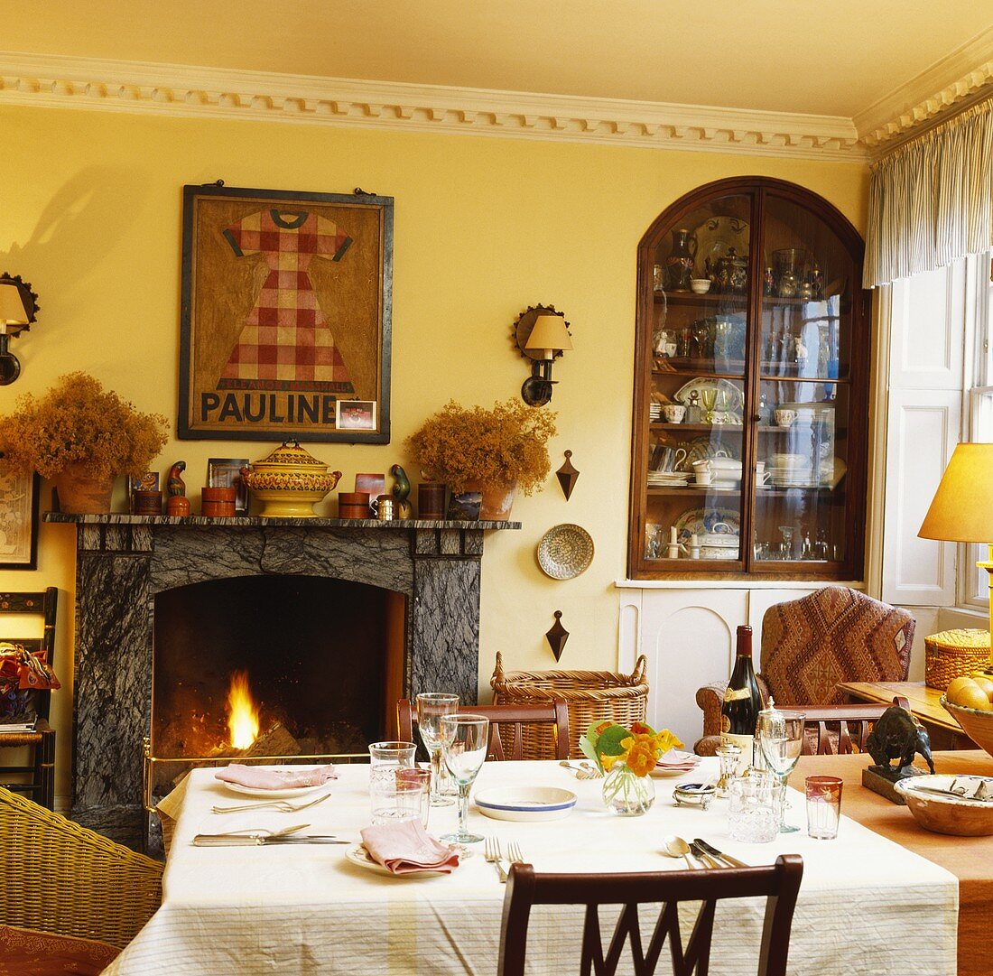 Gedeckter Tisch in Wohnzimmer mit Kaminfeuer und Einrichtung in rustikal-traditionellem Stilmix