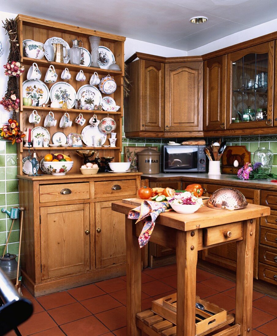 Arbeitsblock und Anrichte aus Kiefer in kleiner, traditioneller Küche mit Sammlung bemalter Teller und Tassen