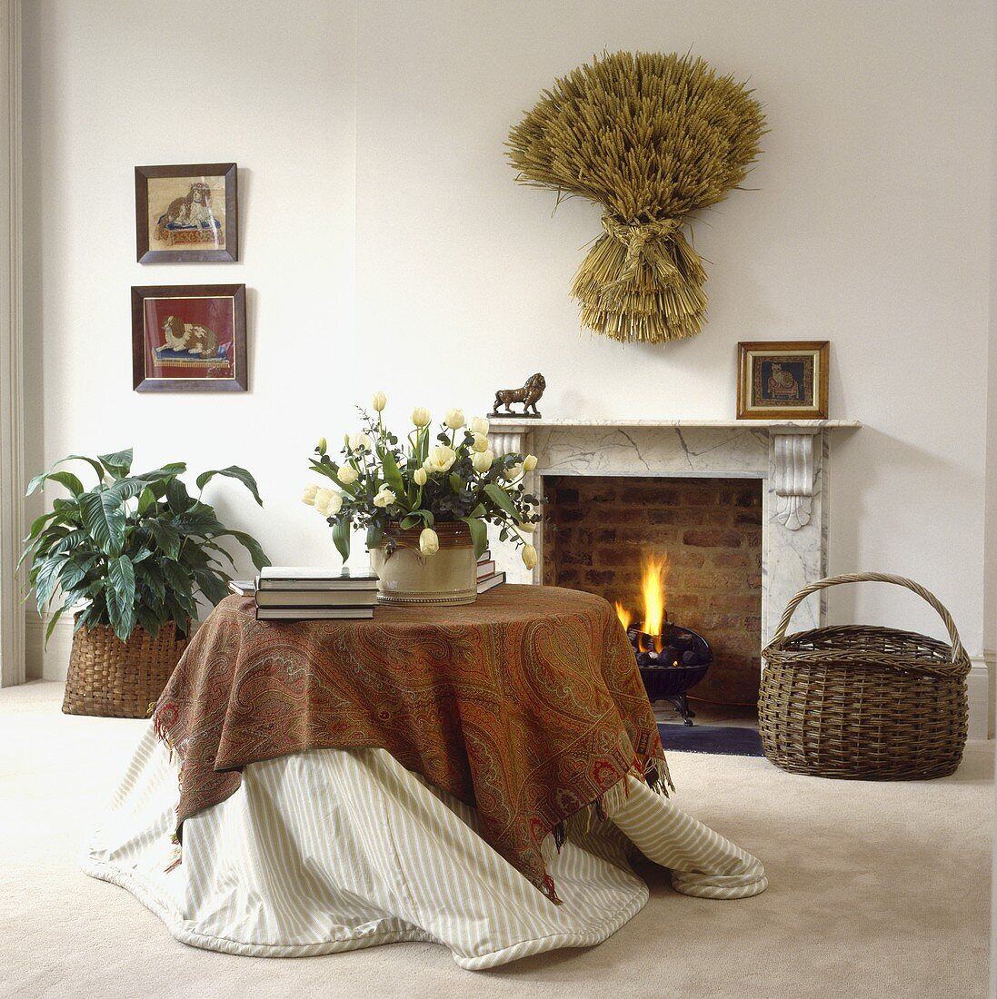 Ein runder Tisch mit Paisley Tuch vor dem Kamin in einem Wohnzimmer