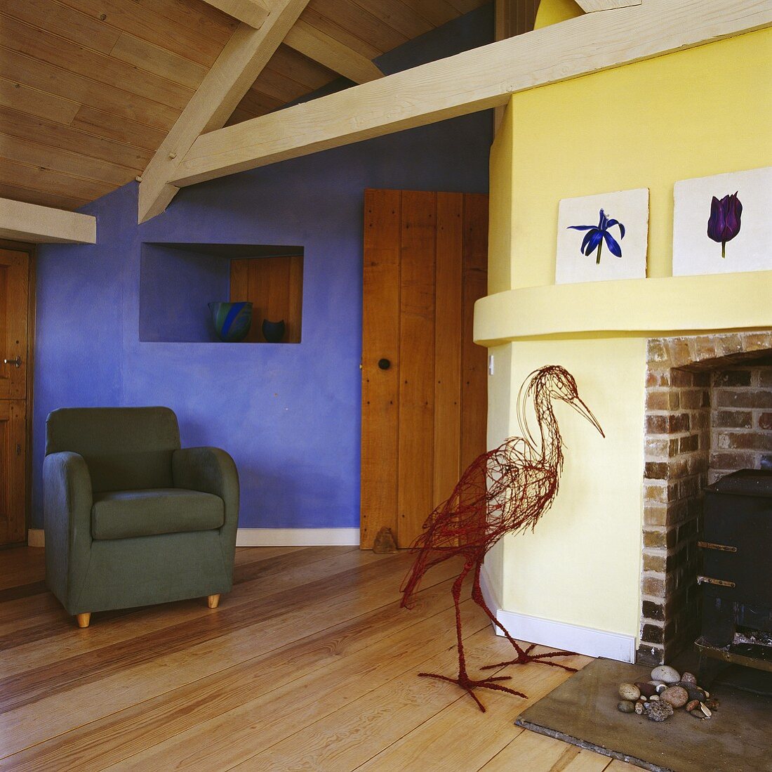 Eine Storchfigur aus Weiden vor dem Kamin in einem Wohnzimmer mit gelben und blauen Wänden