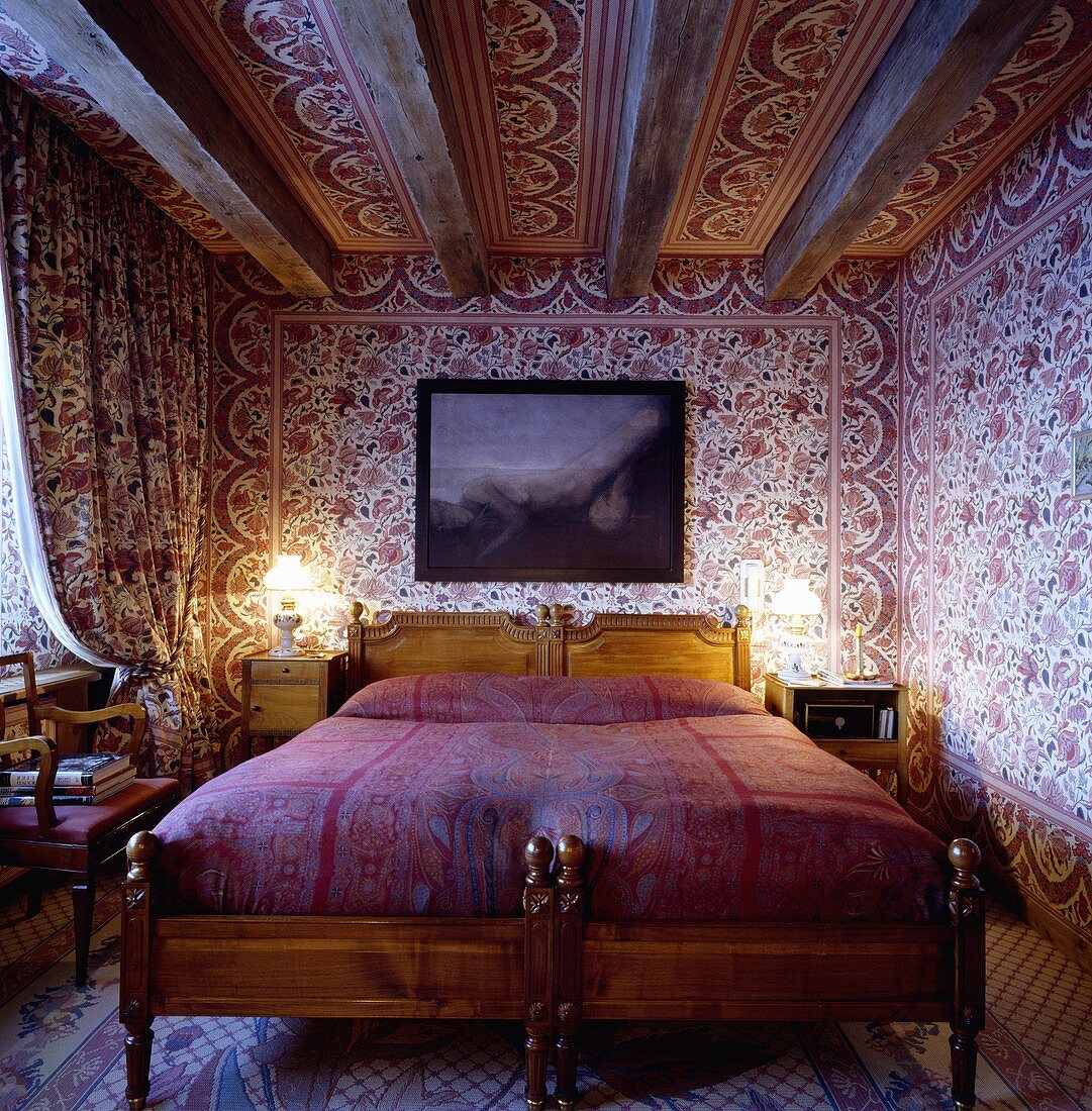 Schlafzimmer mit rot-weisser, indischer Baumwolltapete an den Wänden und an der Decke, Doppelbett und darüber hängendem Bild