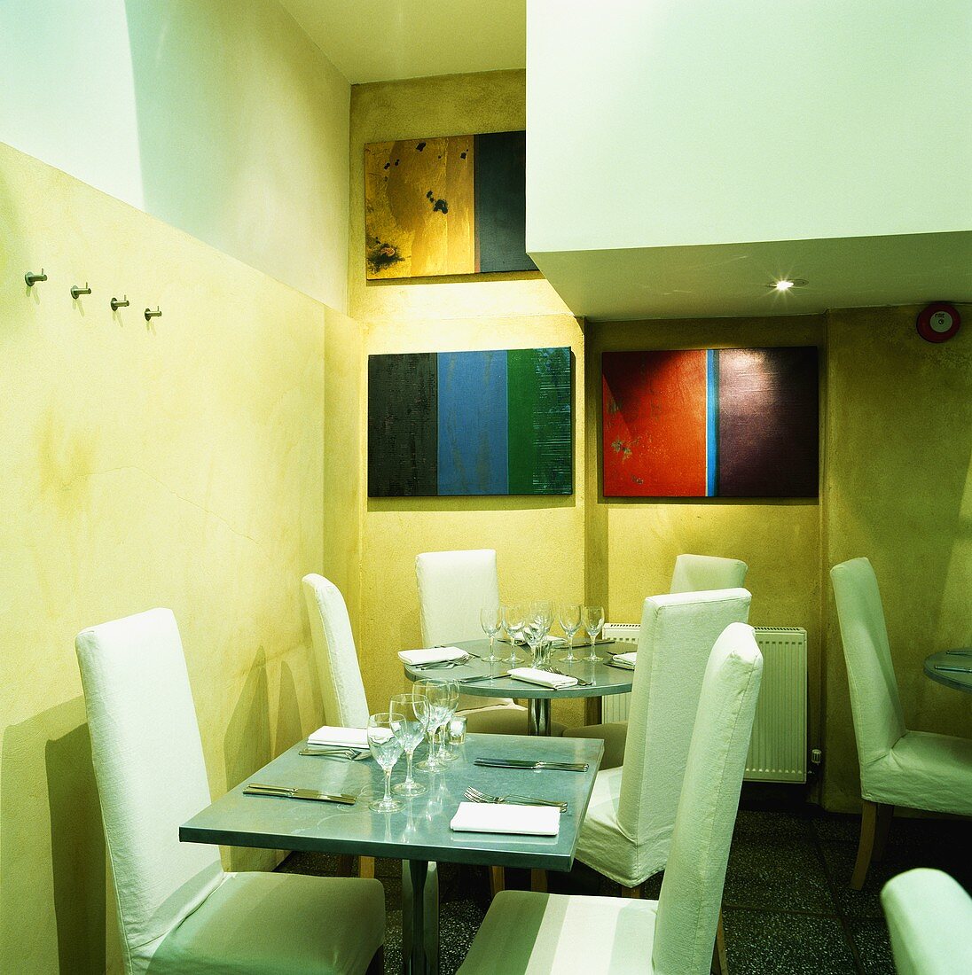 Moderne Tische mit Stühlen in einem Restaurant mit bunten Bildern an den Wänden