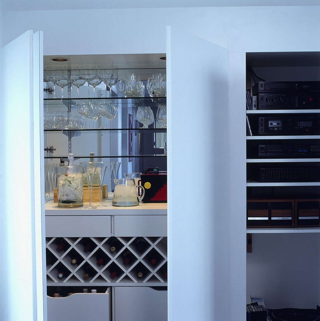 Barutensilien, Gläser und Weinregal in einem Schrank mit weissen Türen