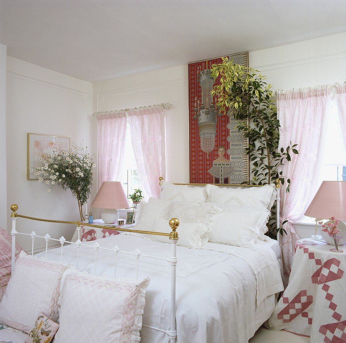 Messing-Bett mit weisser Bettwäsche und rosa Vorhänge in einem Schlafzimmer