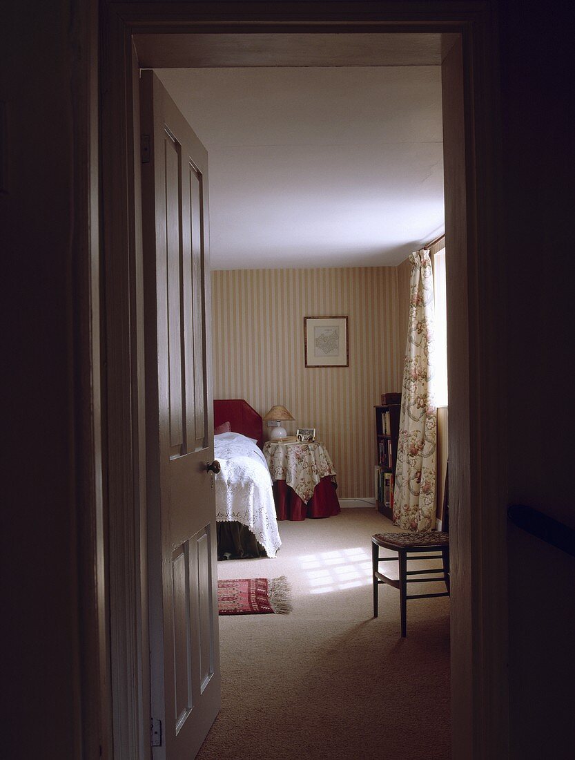 Blick in ein traditionelles Schlafzimmer mit cremefarbenem Teppich und gestreifter Tapete