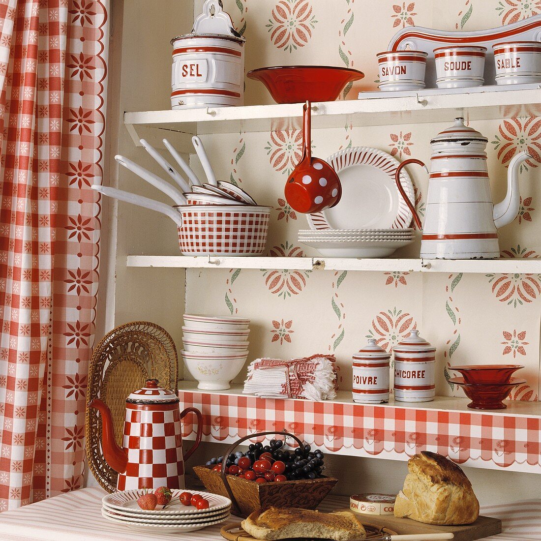 Rot-weisses Geschirr in einem Küchenregal mit rot-weiss karierten Gardinen