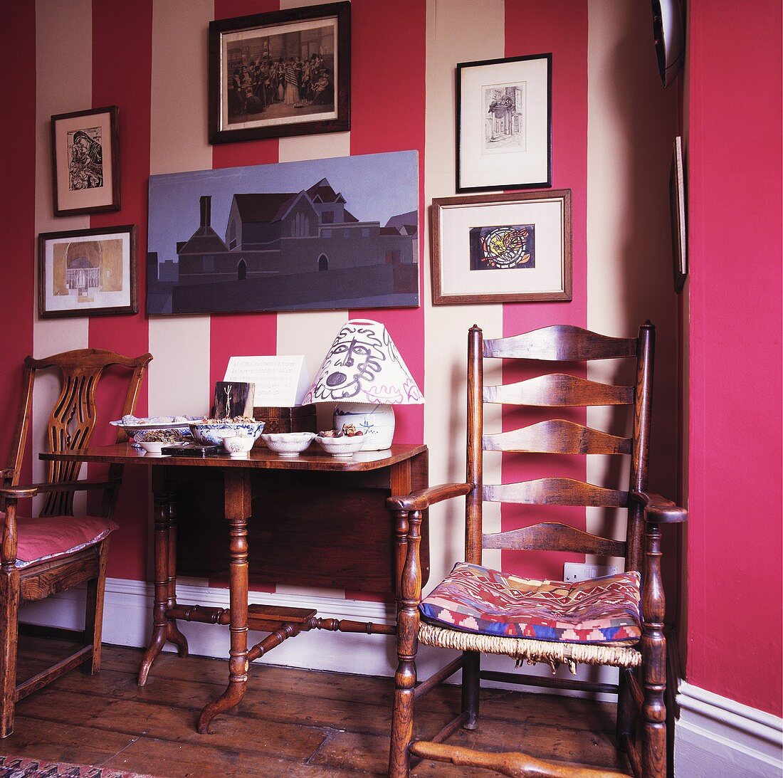 Antiker Stuhl und Tisch vor moderner rot weiß gestreifter Wohnzimmerwand