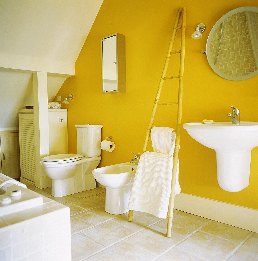 Leuchtend gelbe Wand in einem sonst weissen Badezimmer