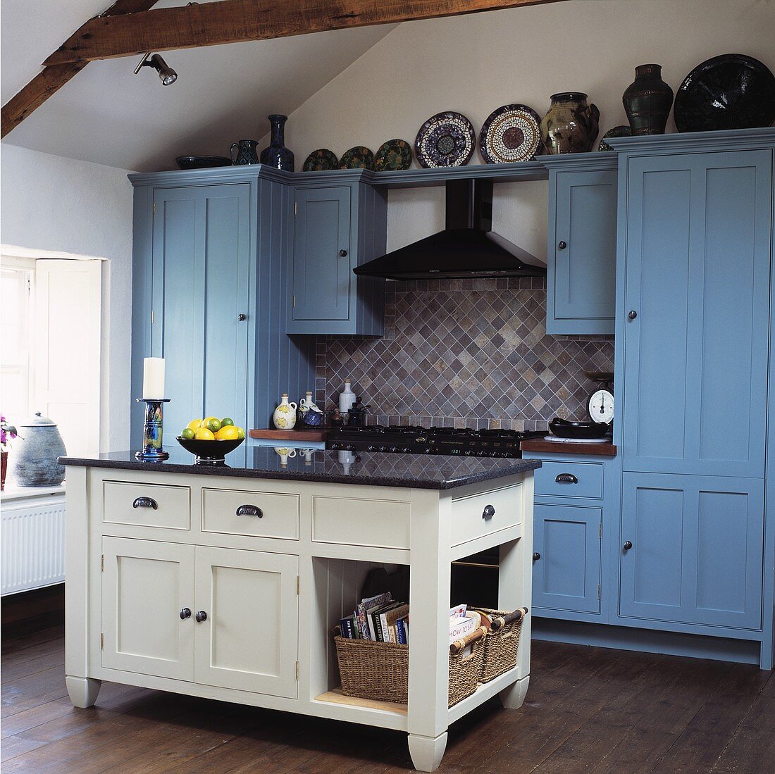 weiße freistehende Küchentheke vor Küchenschrank und -zeile mit blau getönten Fronten im Landhausstil